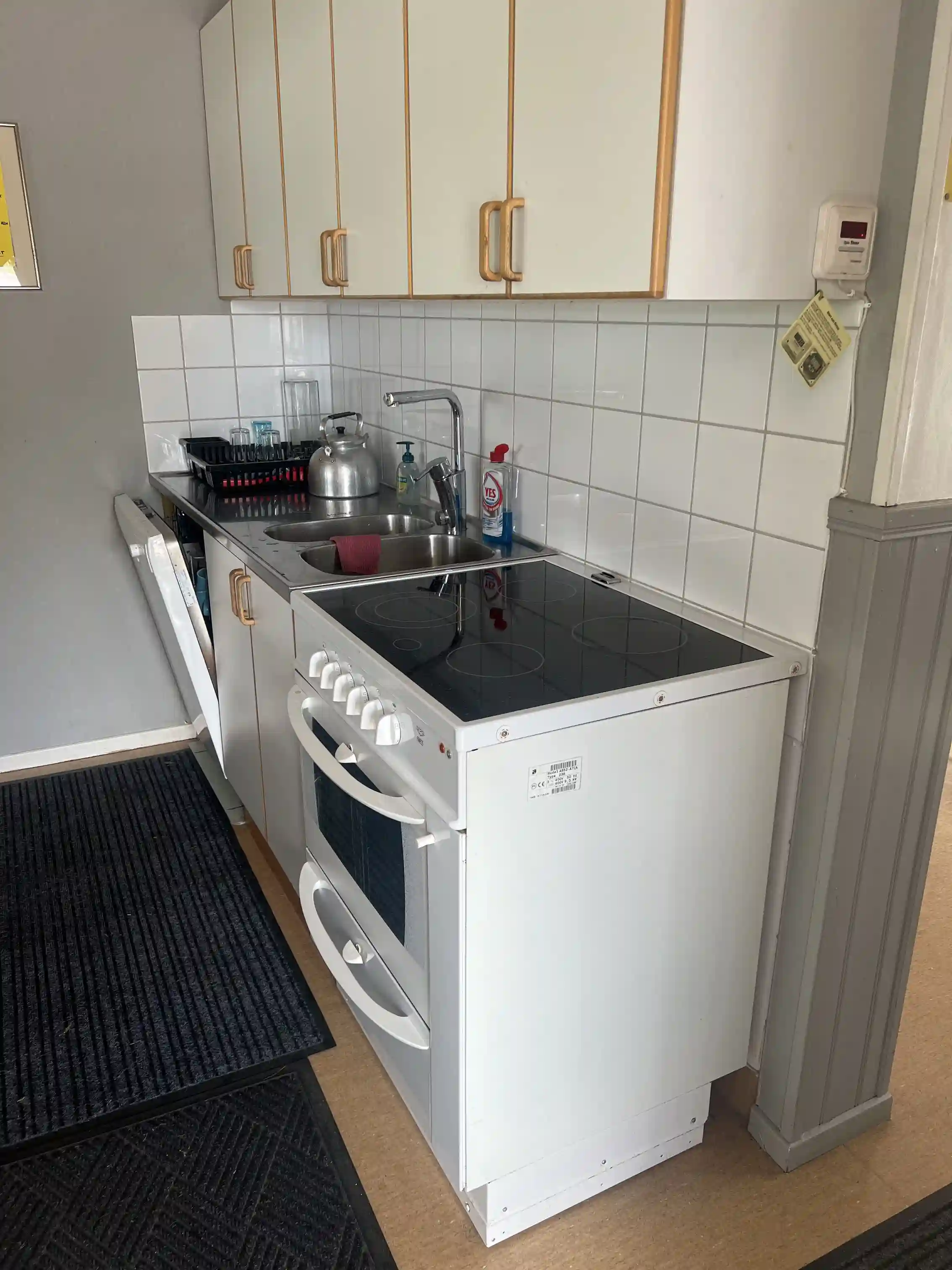 En välordnad köksmiljö med fokus på en modern spis och köksbänk, blanka ytor och golv syns i förgrunden.