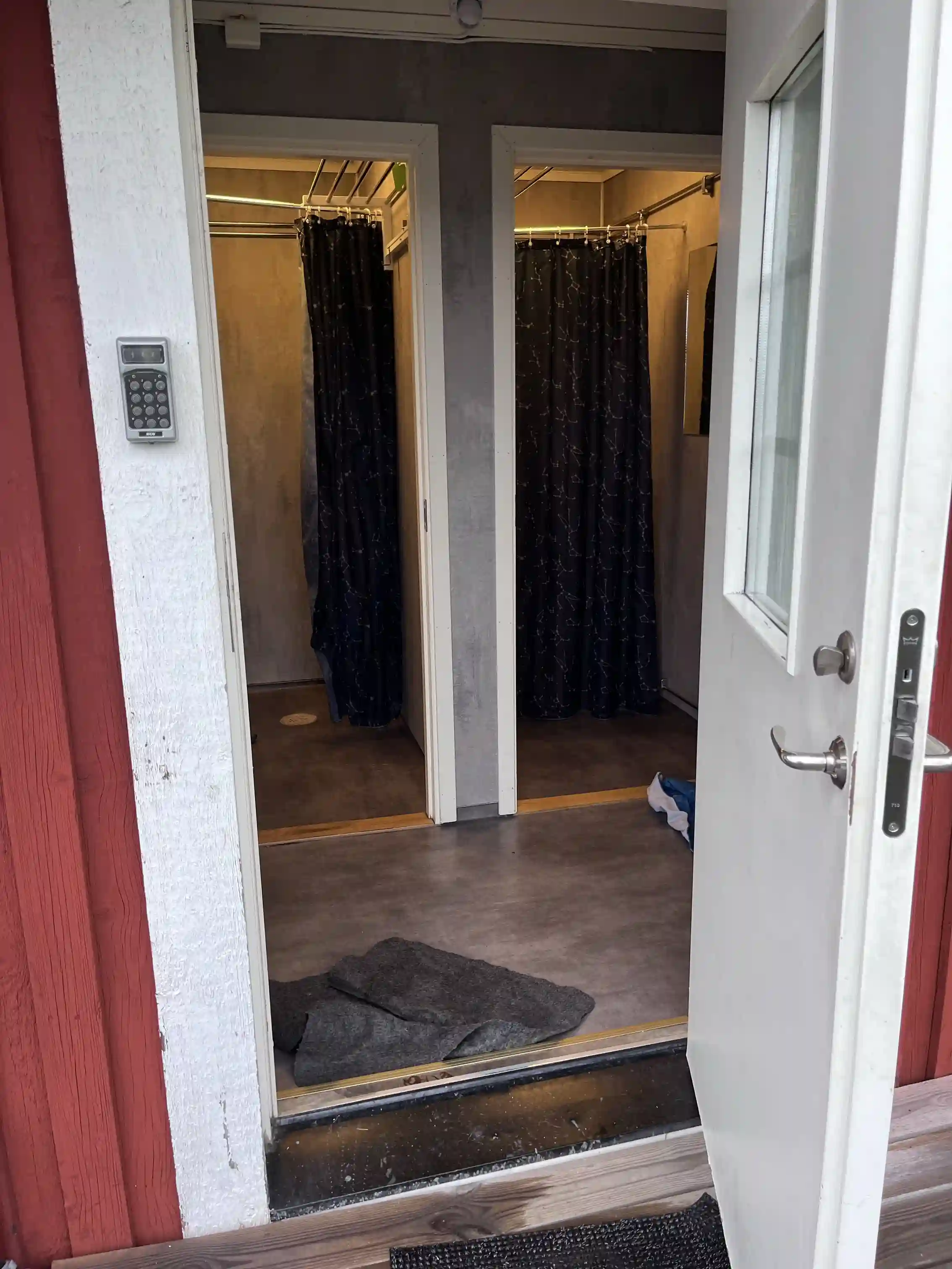 En interiörbild på Arvika småbåtshamn, med fokus på ett välpolerat trägolv och en träfärgad dörr med gardiner som släpper in dagsljus.