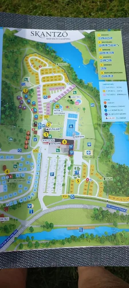 En stor swimmingpool omgiven av gröna träd och solstolar på Skantzö Bad & Camping, ett populärt resmål för avkoppling och familjeaktiviteter.