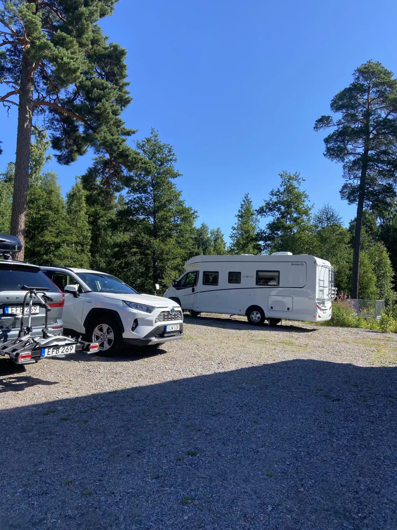 En bil parkerad på Kungsgården Långvind med en registreringsskylt, omgiven av andra fordon och grönska i bakgrunden.
