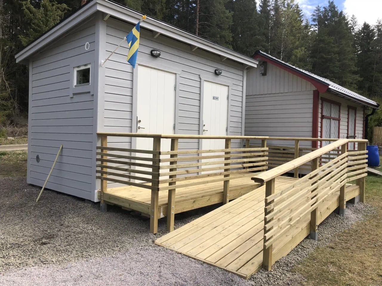 En trätrappa och plankor vid Svennevads camping omgivna av en träräcke och staket, med en rustik atmosfär i skogen.