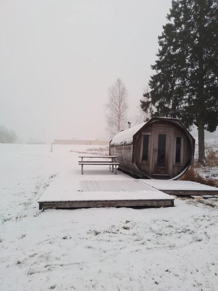 En snöig och frostig vinterdag på Bygdsiljums camping, med tjockt snötäcke och dis i luften, som skapar en kylig och stormig atmosfär.