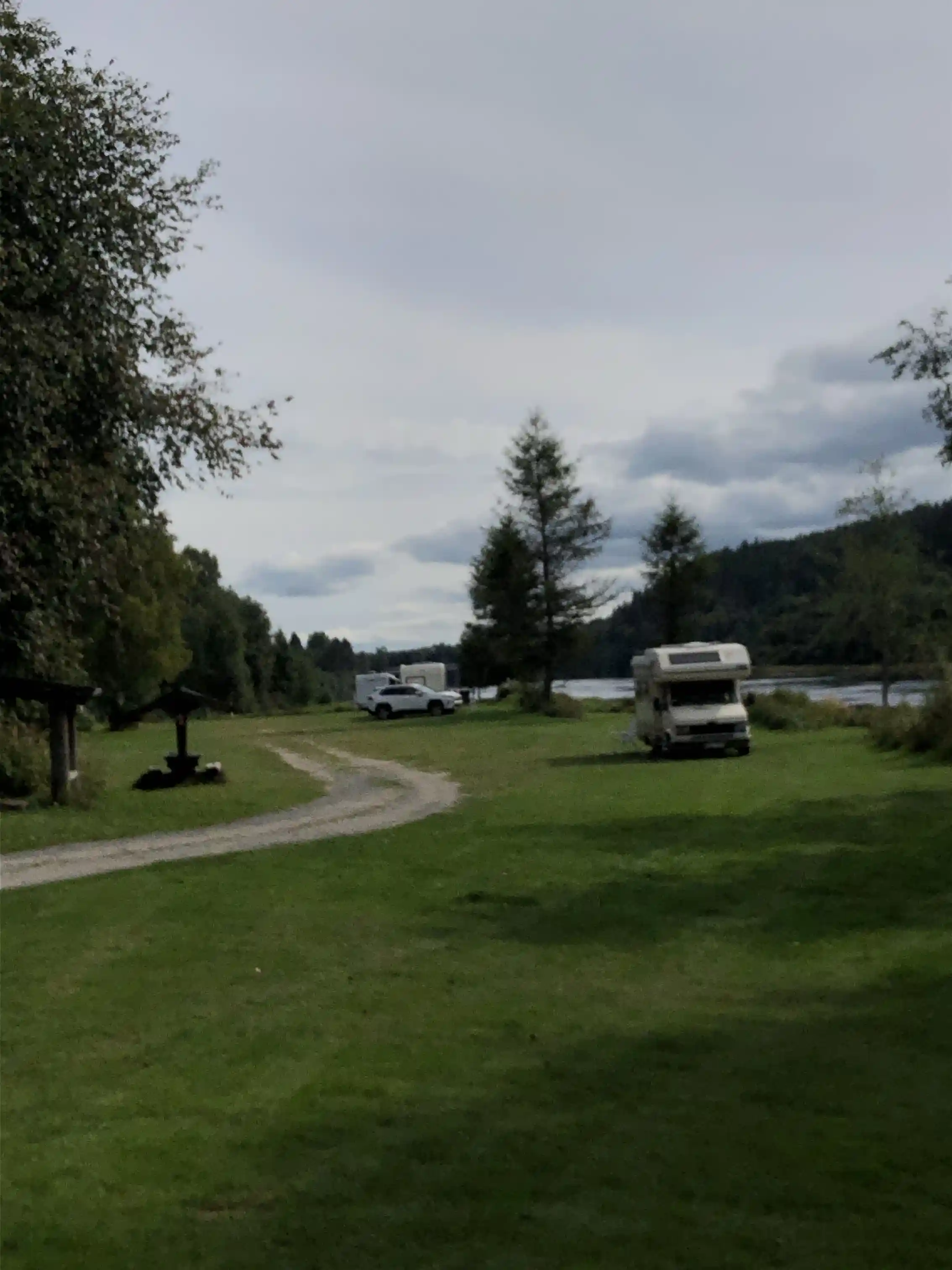 En husvagn och husbil parkerade på en gräsyta vid Värnäs Camping, med en öppen himmel och omgivande natur i bakgrunden.