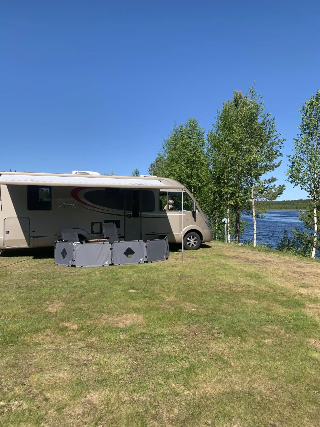 En husbil och flera andra fordon parkerade på Meselefors camping, omgiven av grönska.