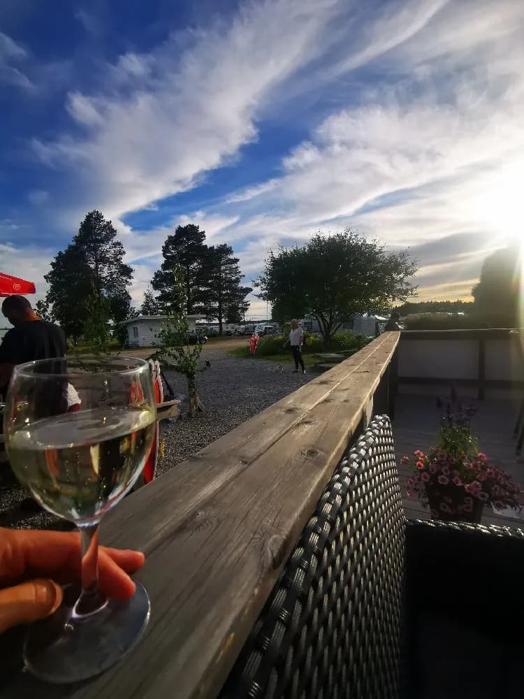 En utomhusmiljö vid solnedgången med utemöbler, inklusive bord och stolar, på Borgaruddens havsbad och familjecamping, vilket skapar en inbjudande atmosfär för besökarna.