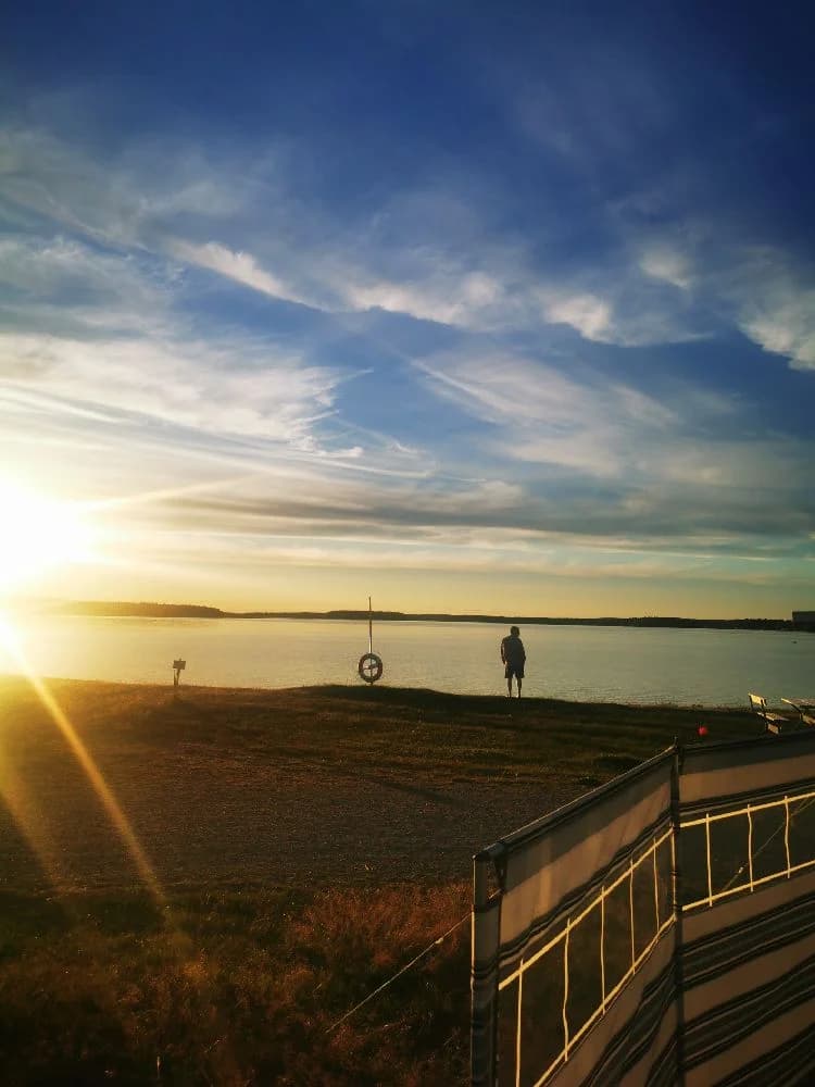En soluppgång över havet vid Borgaruddens havsbad och familjecamping med en klar himmel och några moln vid horisonten.