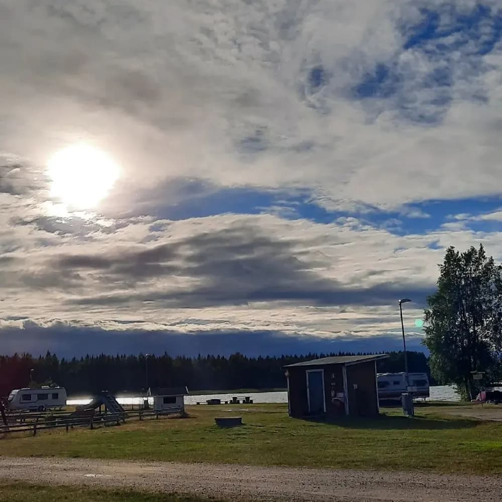 En solnedgång över Borgaruddens havsbad och familjecamping, med en vid horisont och fluffiga moln i kvällssolen.