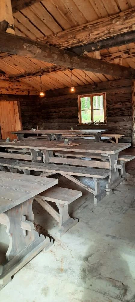 En träbänk på ett golv av träplankor vid Borgaruddens havsbad och familjecamping, omgiven av naturmaterial och trädetaljer.