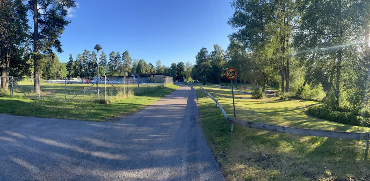 En grönskande campingplats vid Hörsjön med gräsytor, träd och promenadstigar, idealisk för friluftsaktiviteter och avkoppling i naturen.
