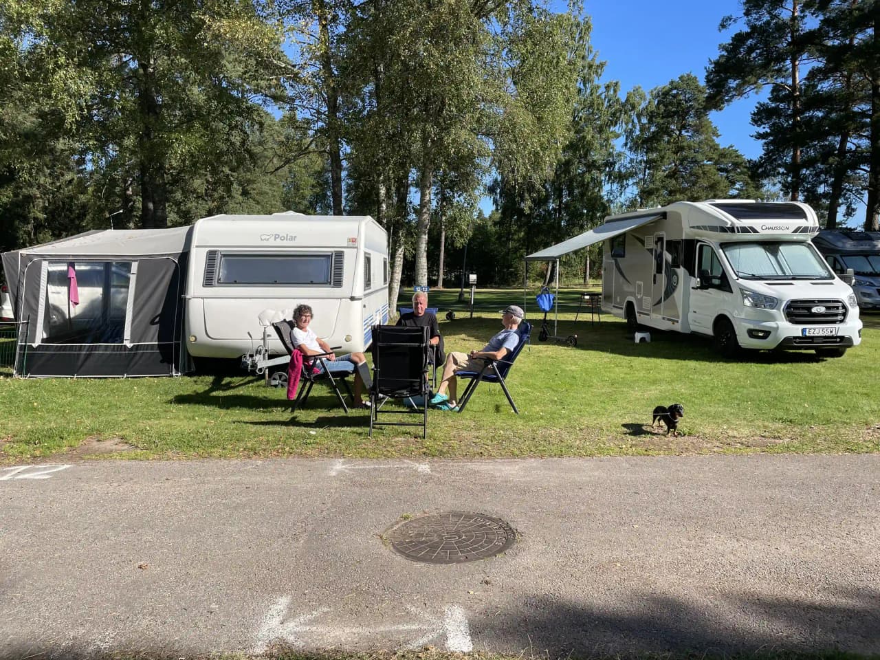 En campingplats vid Hörsjöns camping med husvagnar och husbilar parkerade på gräsplanen. Flera cyklar är parkerade i närheten, vilket framhäver platsens lämplighet för utomhusaktiviteter och rekreation.