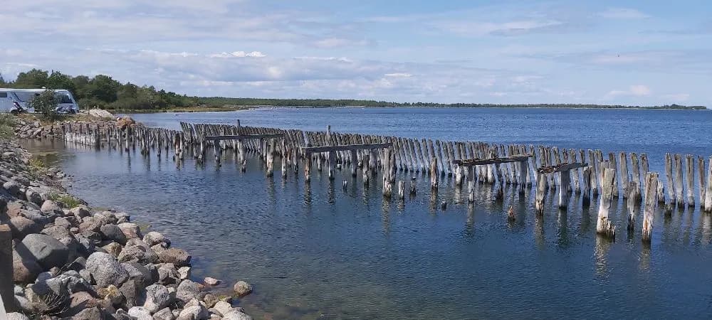 En vy över Böda Hamns Camping med kustlinjen i bakgrunden, där havet och himlen möts vid horisonten.