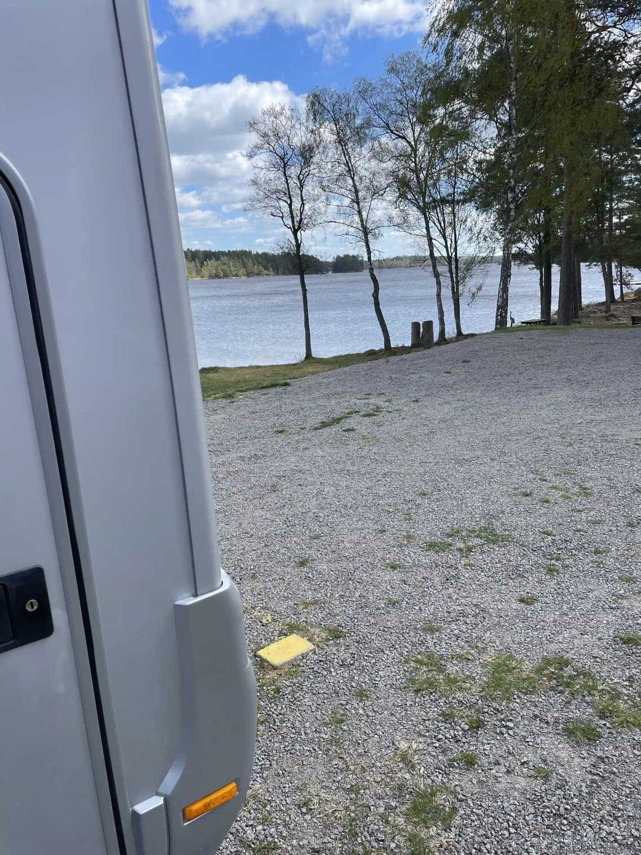 En parkering med ett antal husbilar och husvagnar uppställda i Uvaparken ställplats, omgivna av grönska.