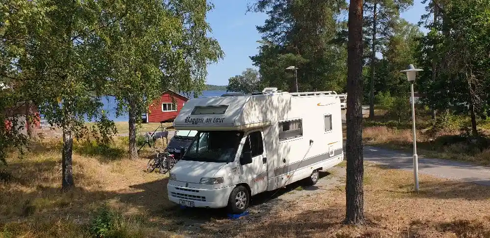 En husbil parkerad på Uvaparken ställplats, omgiven av andra husbilar och fordon.