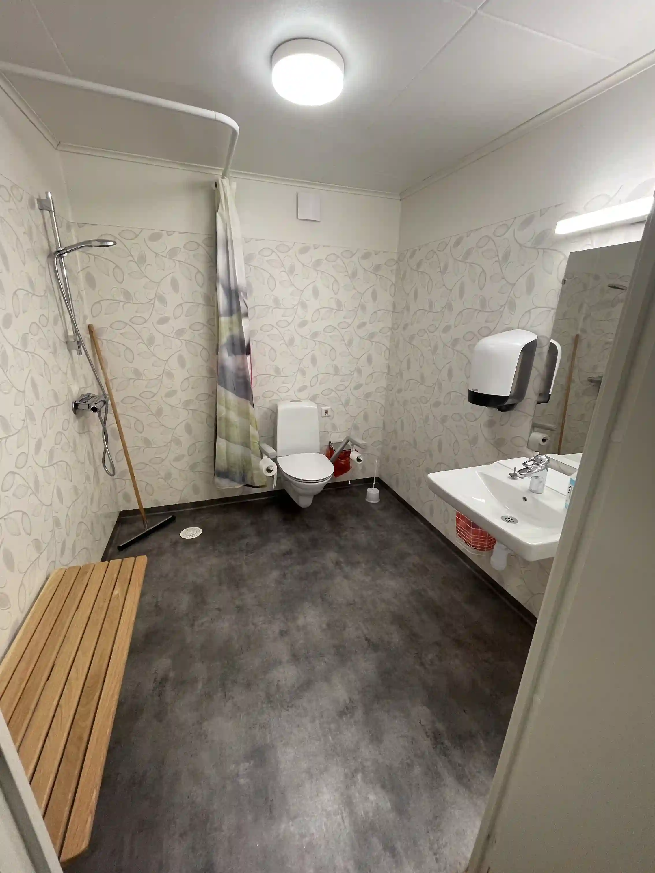 En modern och ren badrumsinredning med kaklade väggar och golv, utrustad med en vit toalettstol och ett matchande toalettlock.