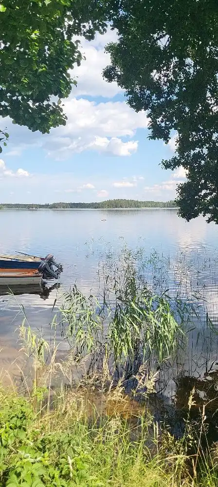 En solig dag vid Horndals Bad & Camping med klarblå himmel och moln. Vattnet i sjön glittrar och omges av grönska.