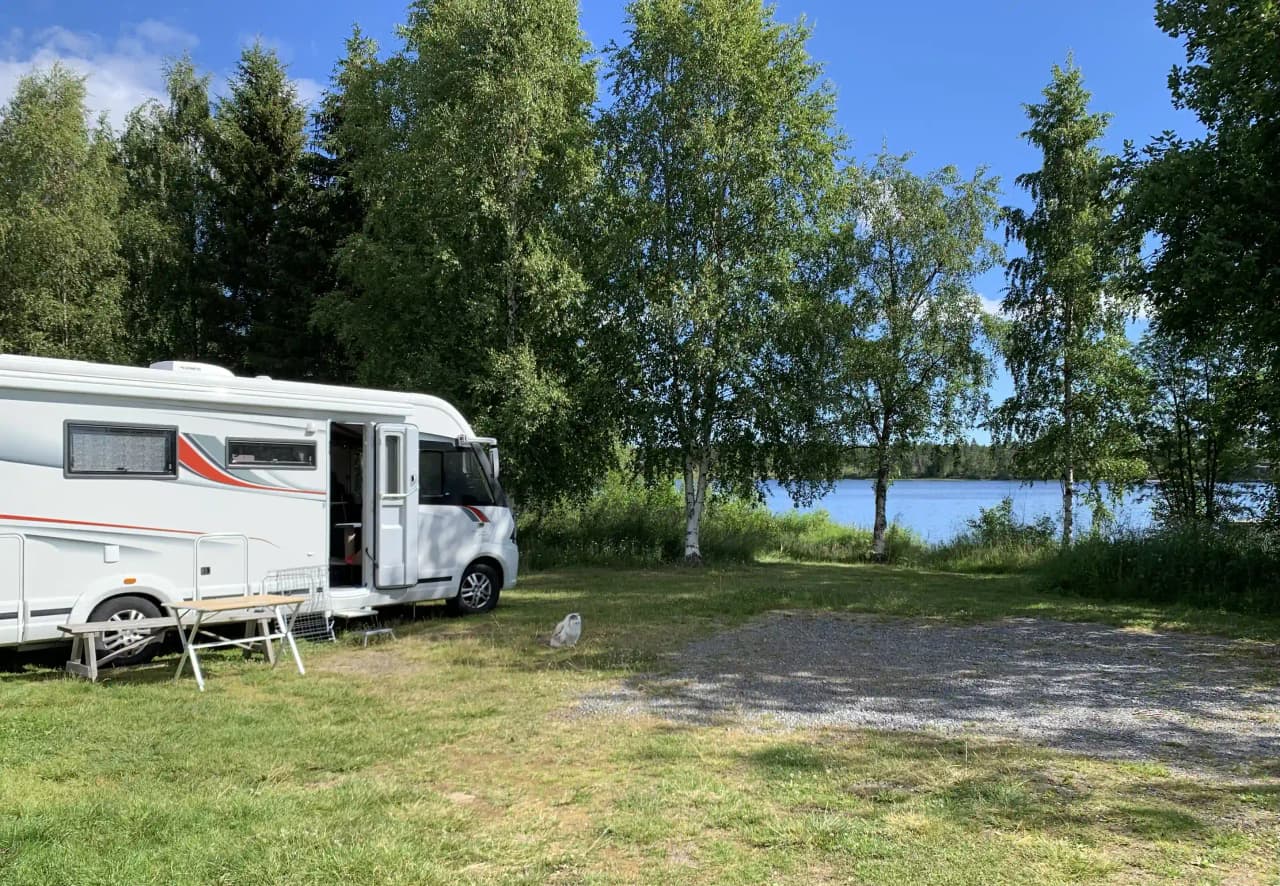 En bild av Sikeå Havscamping med uppställda husvagnar och husbilar på en campingplats nära vatten.