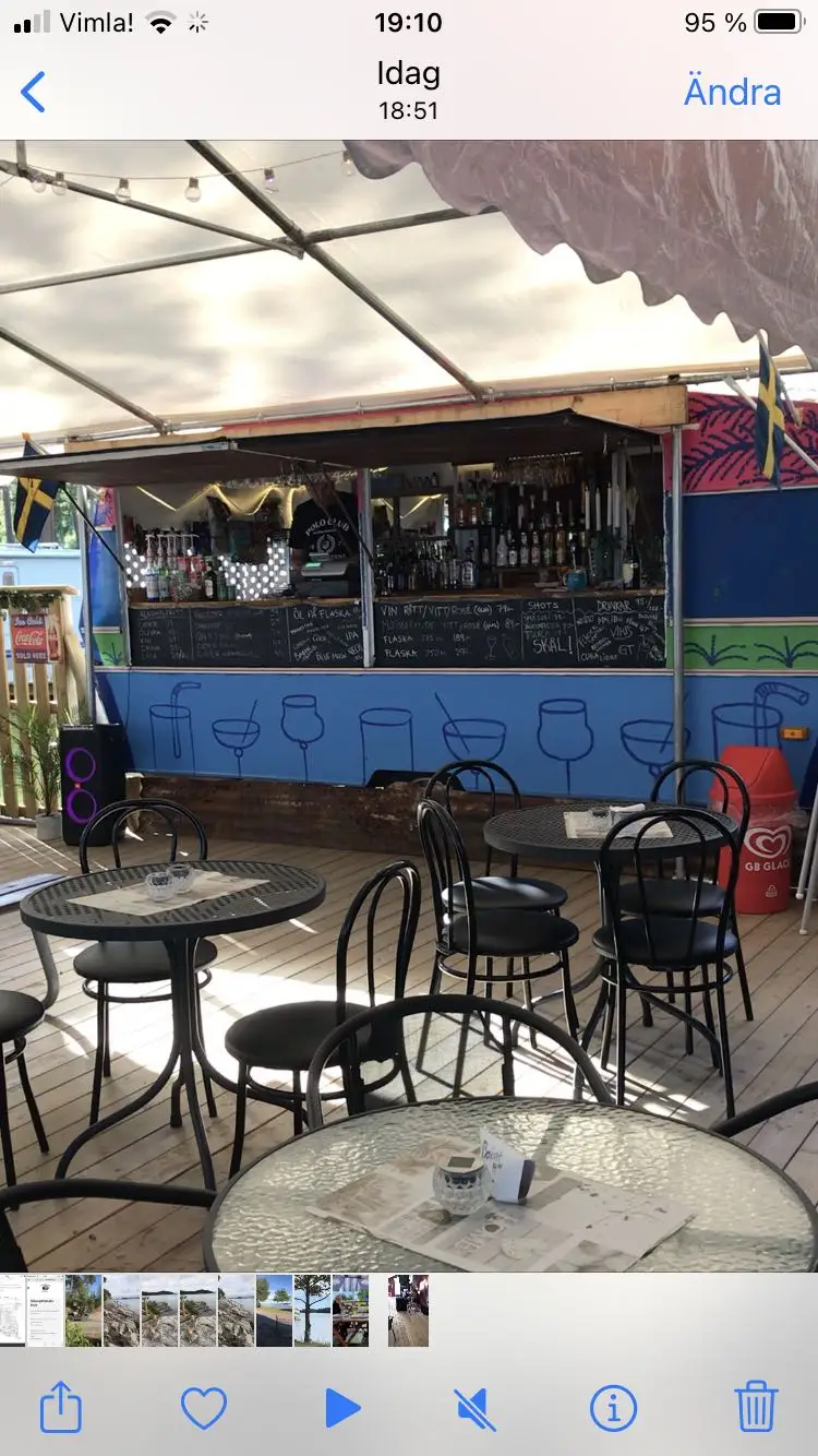 Utomhusmiljö vid Strandstuvikens Havsbad & Camping med solstolar och bord under skuggande parasoller, omgiven av friluftsmöbler.