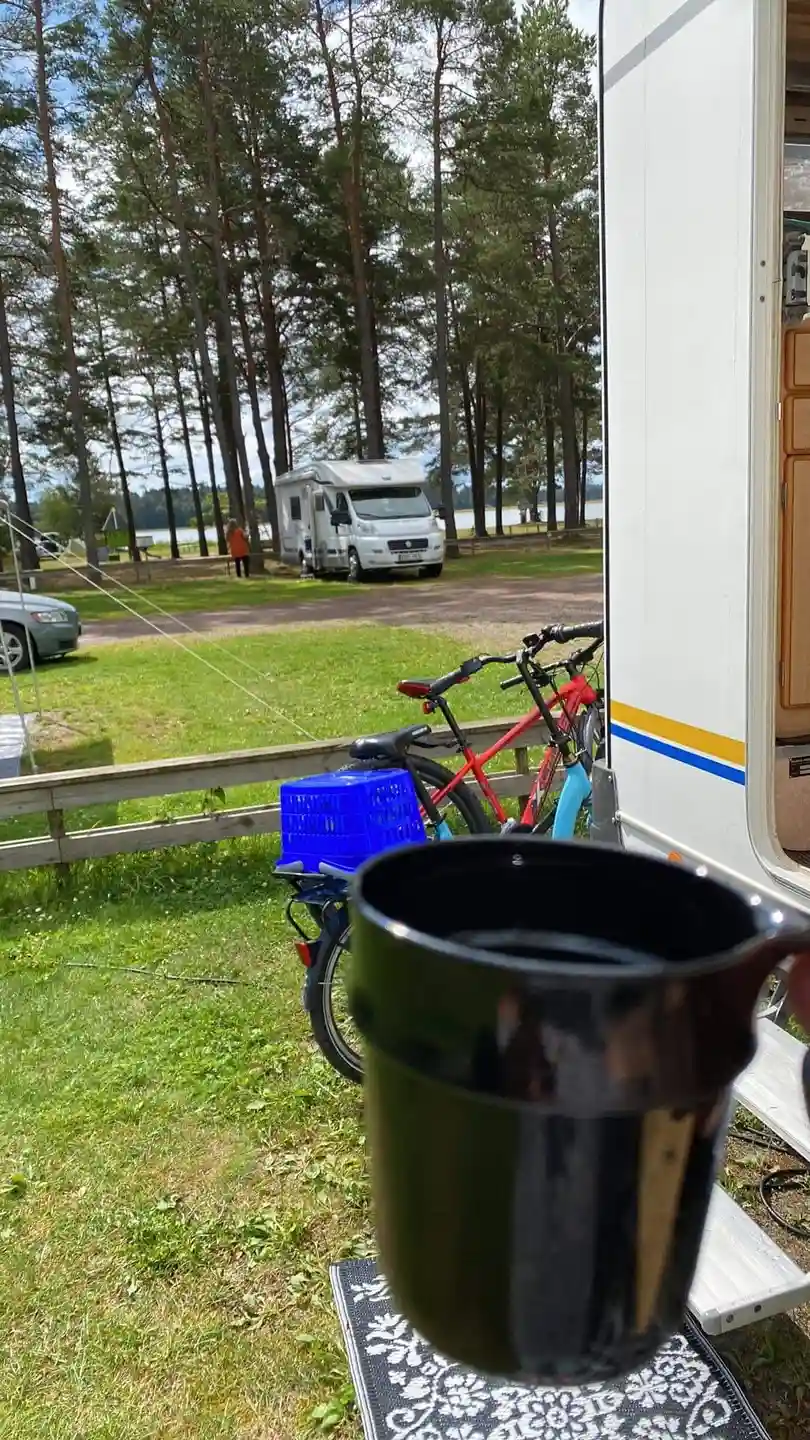 En cykel står parkerad vid Strandstuvikens havsbad & camping. Cykelns hjul, ekrar och styre är synliga. I bakgrunden skymtar campingområdet.