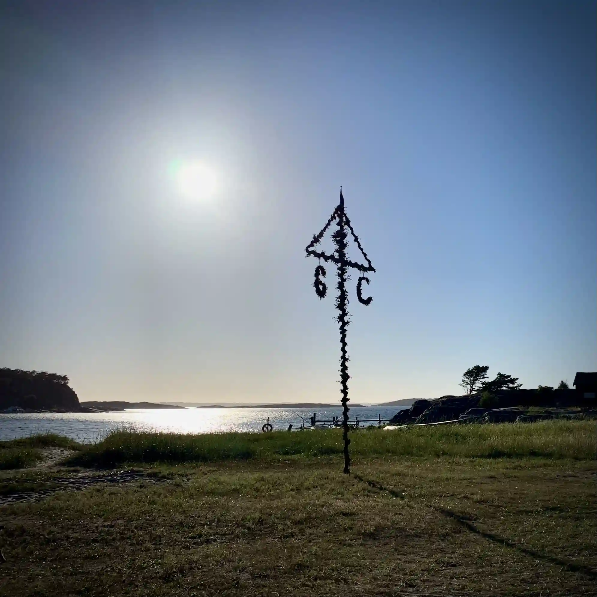 En vacker kvällsbild över Garviks Camping. Silhuetten av en flaggstång syns mot horisonten, medan solens sista strålar skapar ett varmt ljus över kustlinjen.