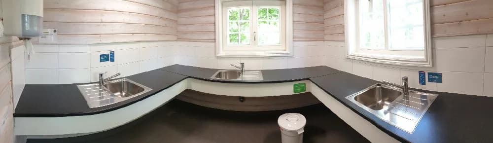 En ljus trästuga med vackra, glänsande trägolv och en rustik men hemtrevlig interiör. Stugan har stora fönster för naturligt ljusinsläpp, vilket skapar en inbjudande atmosfär.