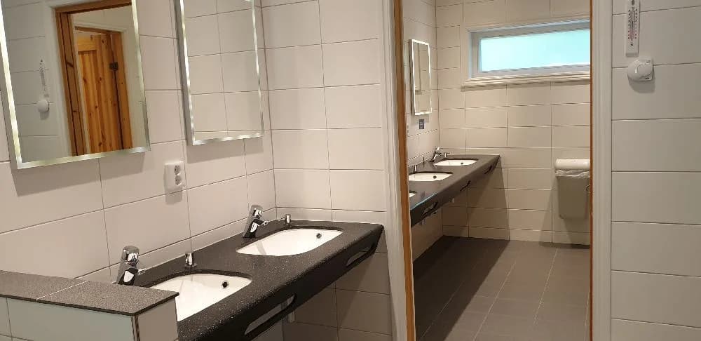 Ett modernt badrum med ett stilrent handfat och kran. Väggarna och golvet är i ljusa toner, vilket ger ett fräscht och inbjudande intryck.