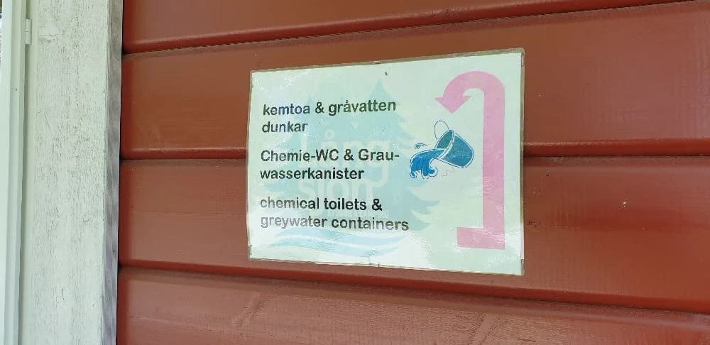 Färgglad skylt för Långsjön Stugor & Camping med trästruktur och reklamtext.