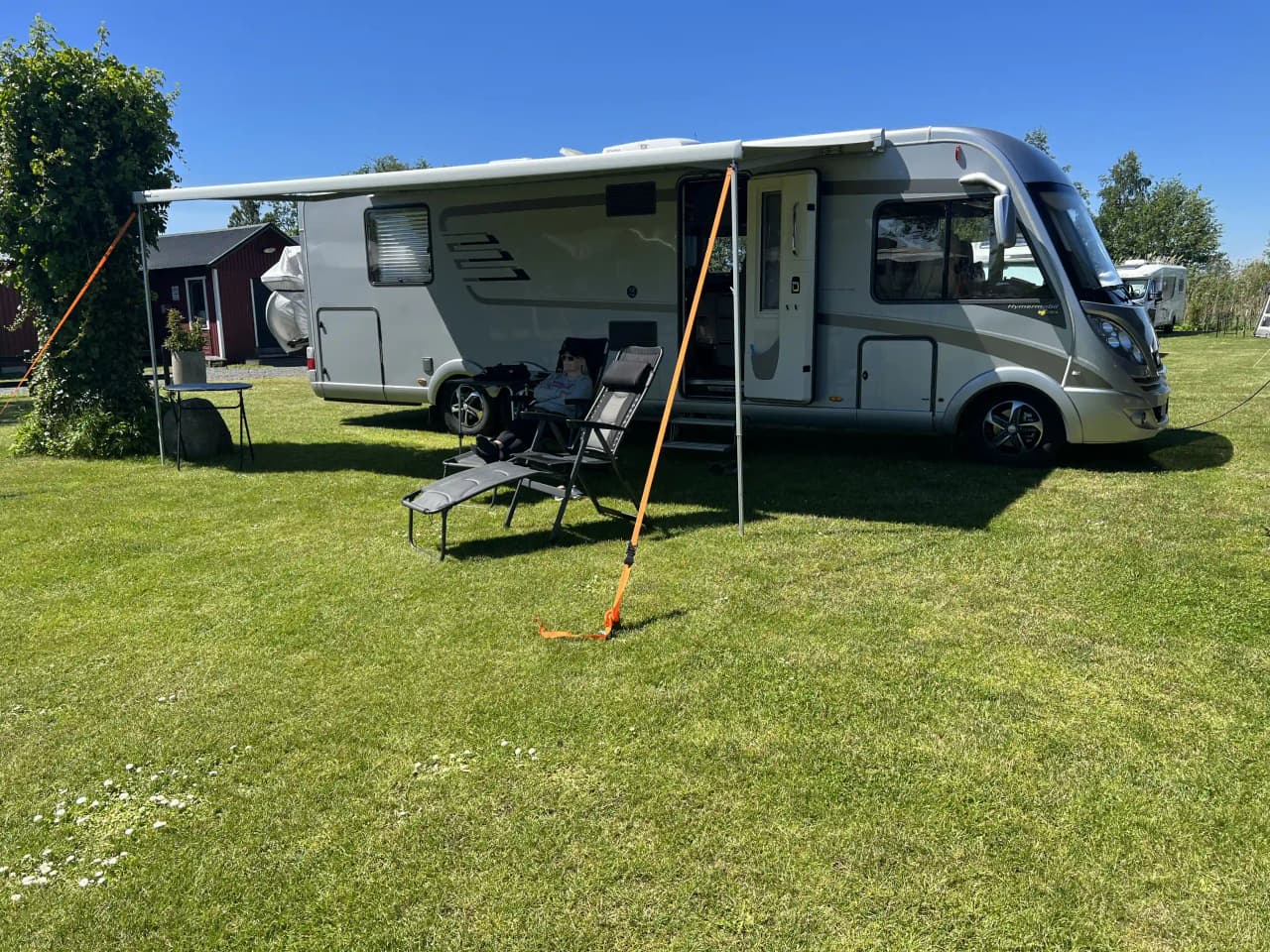 En husvagn och en skåpbil parkerade vid Martins Rökeri och Camping, omgivna av andra campingfordon.