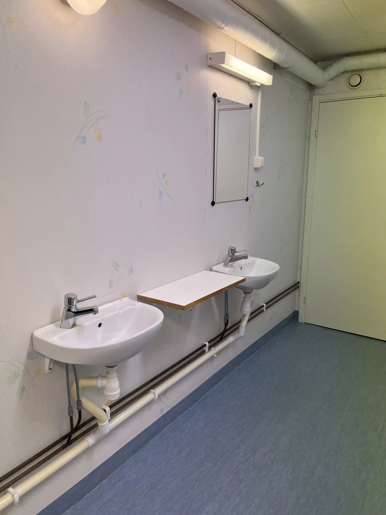 Bild av ett camping-badrum på Martins rökeri och camping, med kaklade väggar, ett handfat, och moderna VVS-armaturer. Golvet är täckt av klinkers och det finns ett vitt tak.