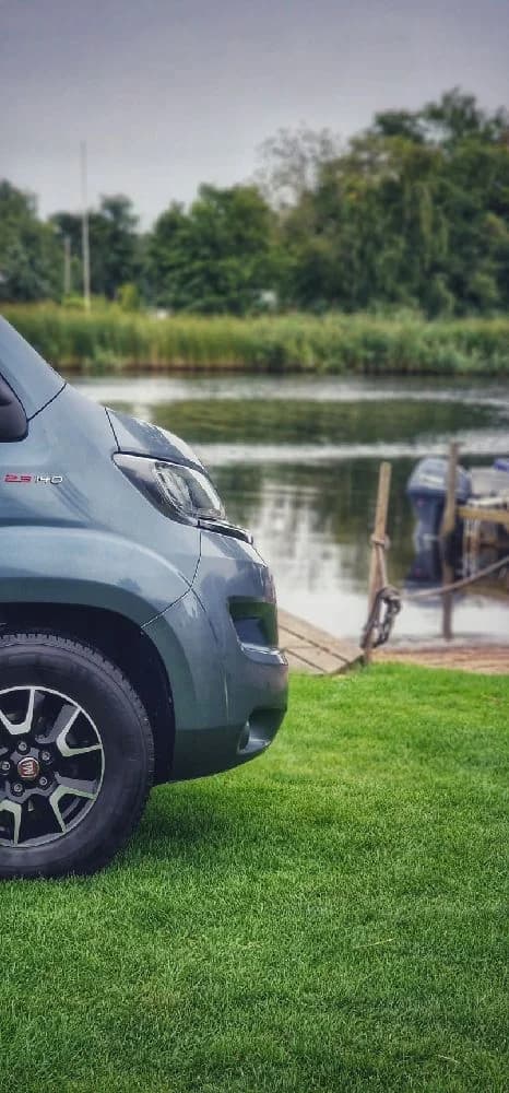 En liten bil parkerad på en gräsyta vid Martins Rökeri och Camping.