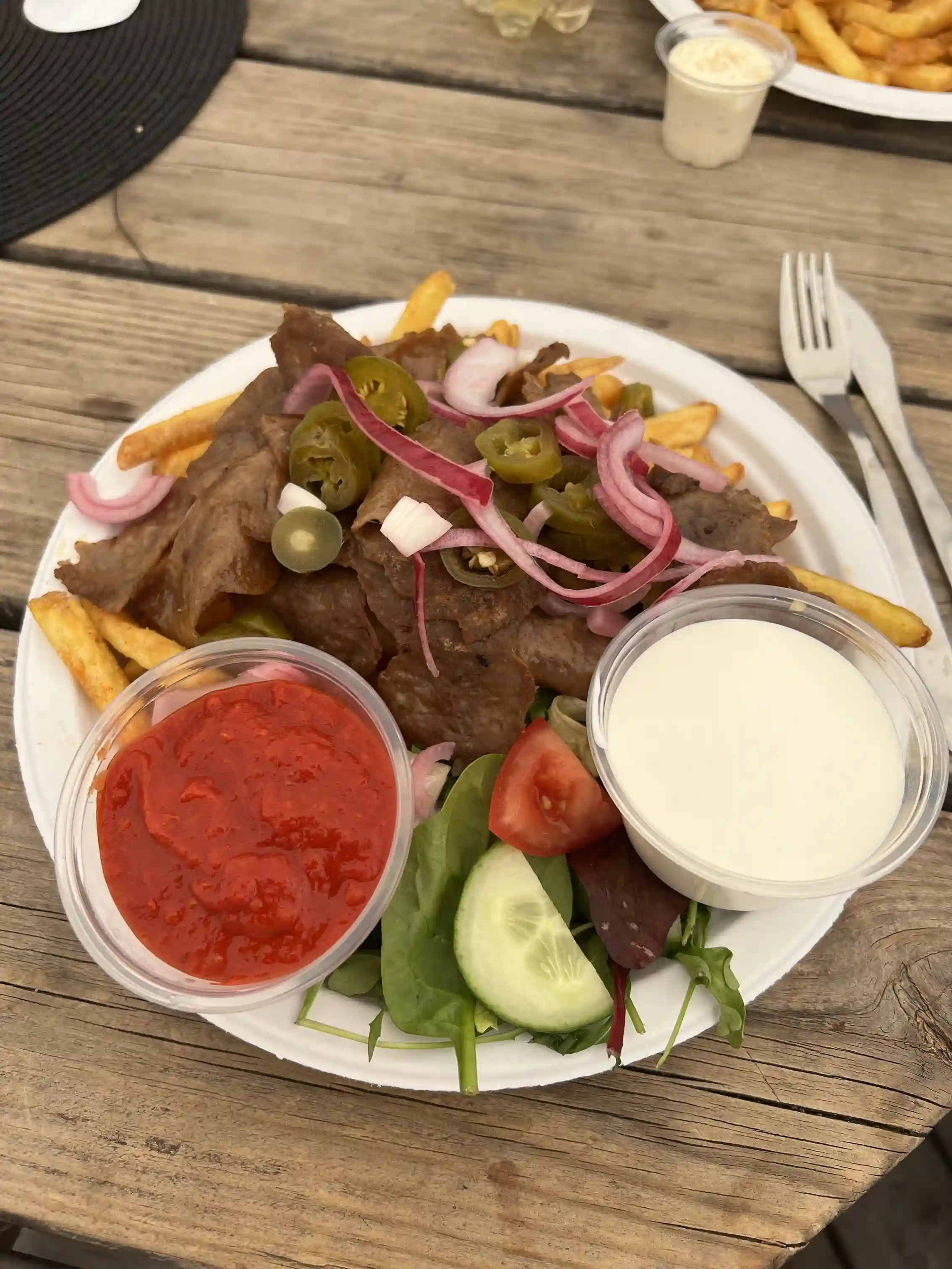 En tallrik med snabbmat, inklusive friterad mat och kött, serverad med grönsaker och en skål med dipp.