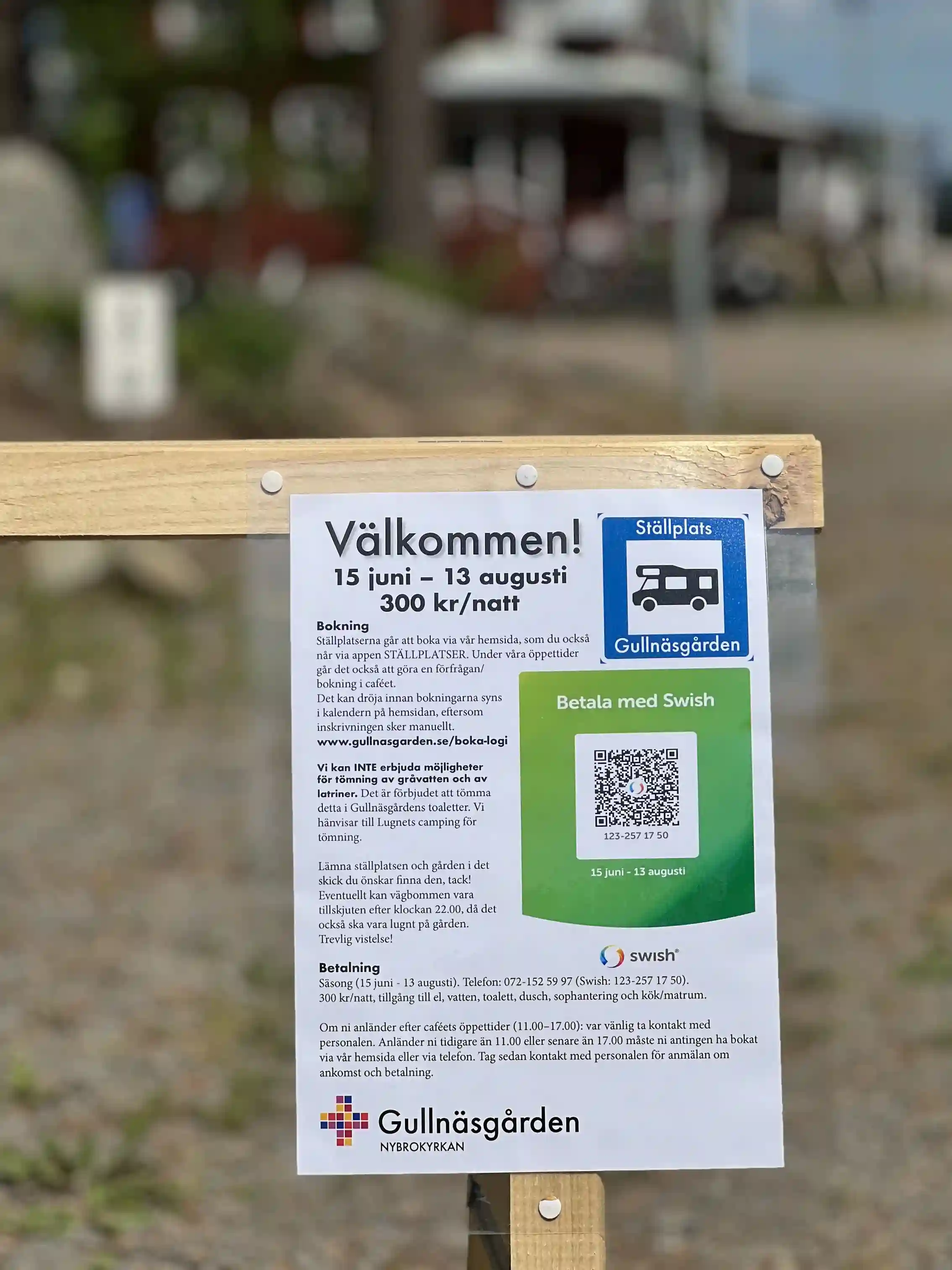 En skylt vid en grusväg som annonserar Gullnäsgården, omgiven av naturlig skogsmiljö.