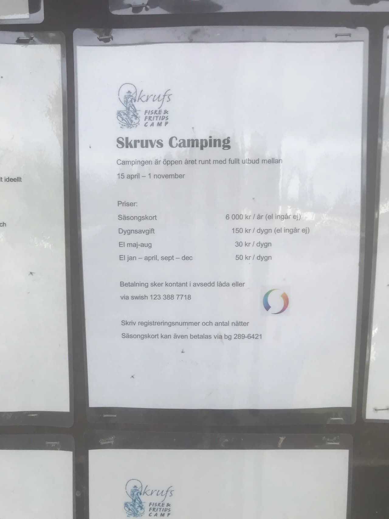 En bild som visar Skruvs vildmarkscamping, med inslag av reklam i förgrunden och natursköna omgivningar i bakgrunden.