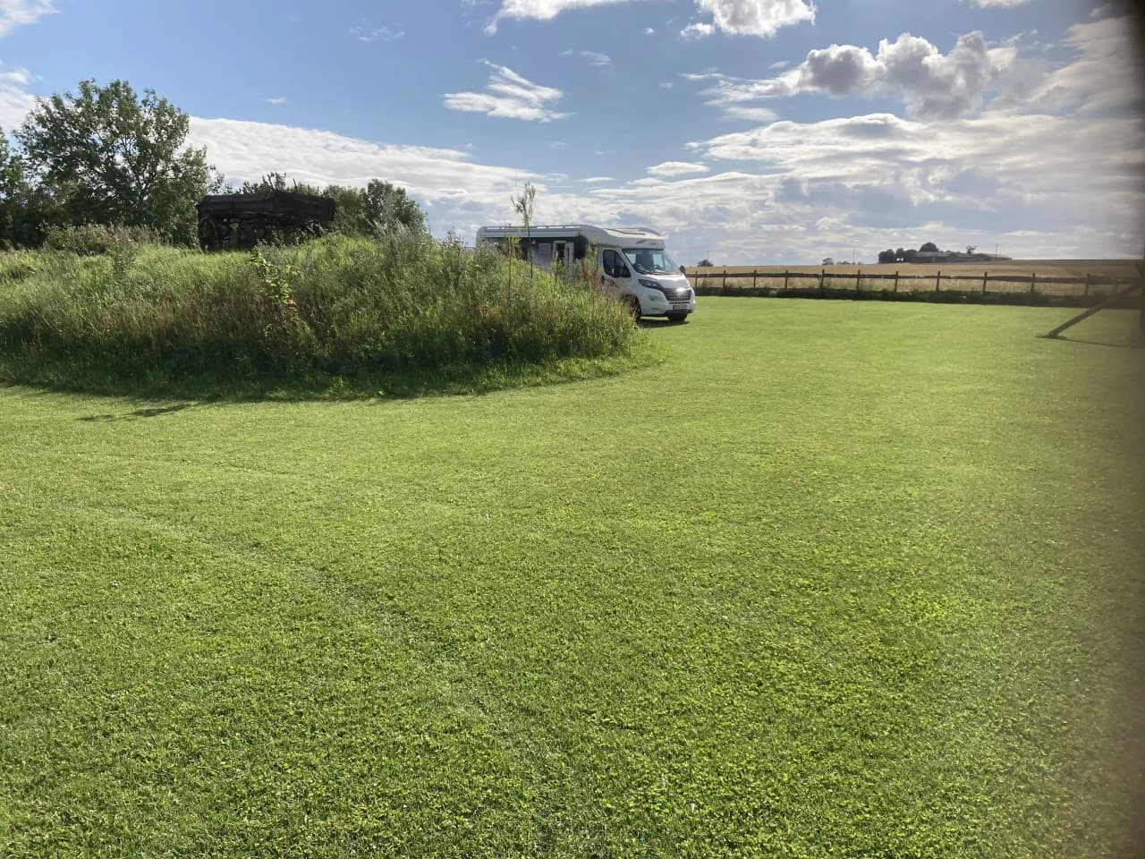 En grön äng vid ställplats Wild West, omgiven av öppna fält och grästäckt mark.
