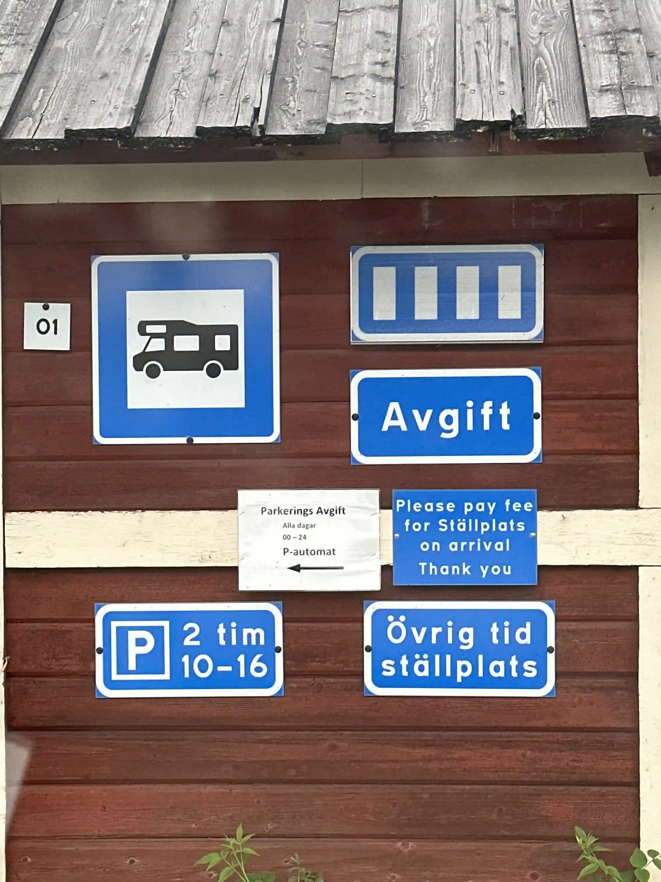 En träskylt med texten "Tännforsens turiststation" monterad på en byggnad med målad träpanel.