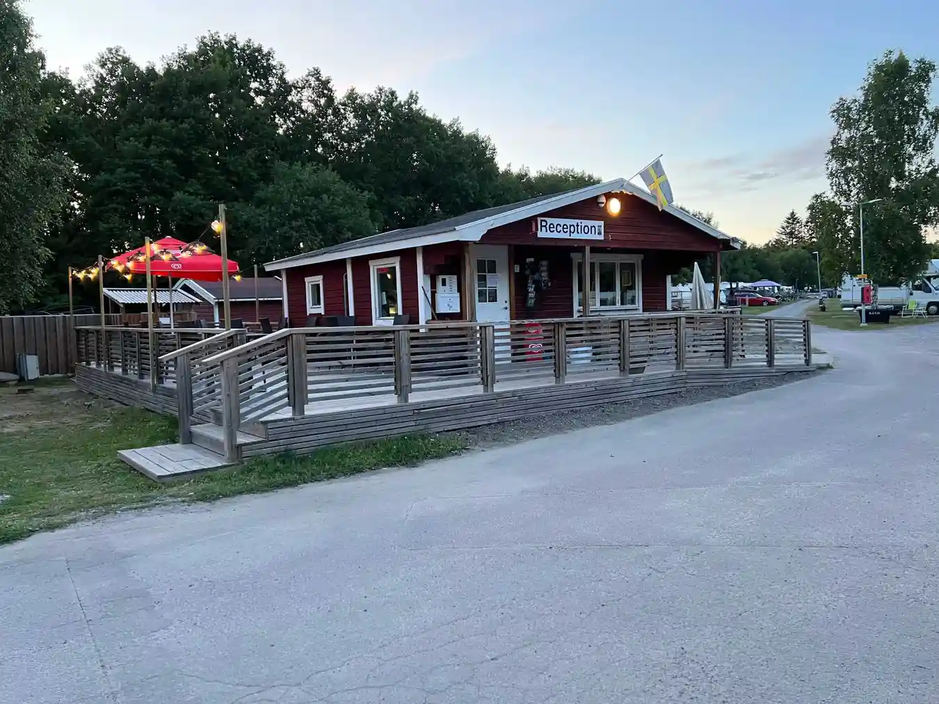 En utomhusrestaurang med picknickbord och bänkar i skuggad miljö vid Mälarbadens camping.
