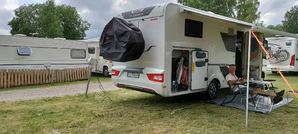 En campingplats på Hargshamns camping med parkerade husvagnar, en husbil, och tält på en grönskande plats.