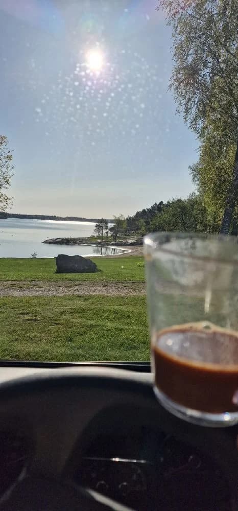 En stilla morgon vid Hargshamns camping med solljus speglat i en sjö, där dricksglas och serveringsartiklar står redo.