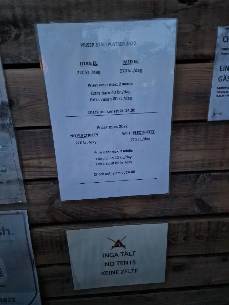 En närbild på en trävägg med handsnidad text som beskriver Hägern Bed & Nature, en naturnära och rustik plats för övernattning och rekreation.