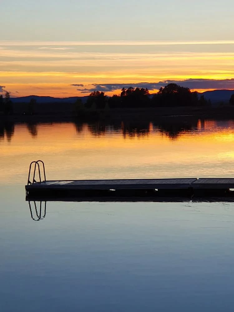 En vacker solnedgång över en stilla sjö med blå himmel och horisont.