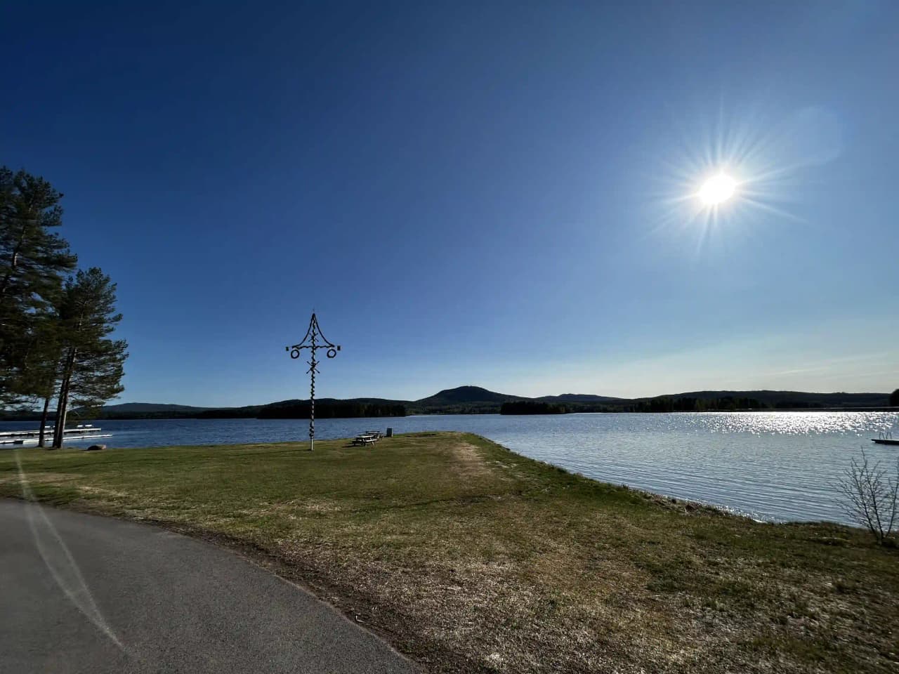 Vy över Sollerö Camping med en horisontlinje där sjön Siljan möter himlen. I förgrunden syns en strandkant med ett grönt landskap längs kusten.
