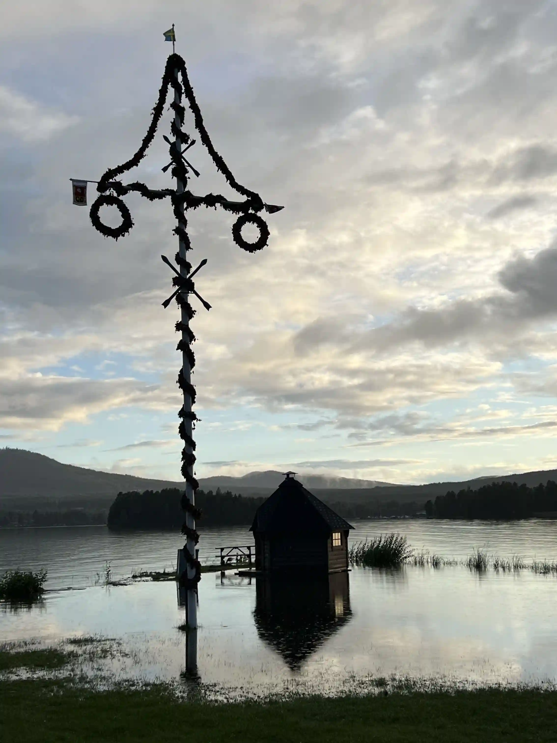 En spegelblank sjö omgiven av frodig, grönskande skog, med en kvällshimmel som reflekteras i vattnet vid Sollerö camping.