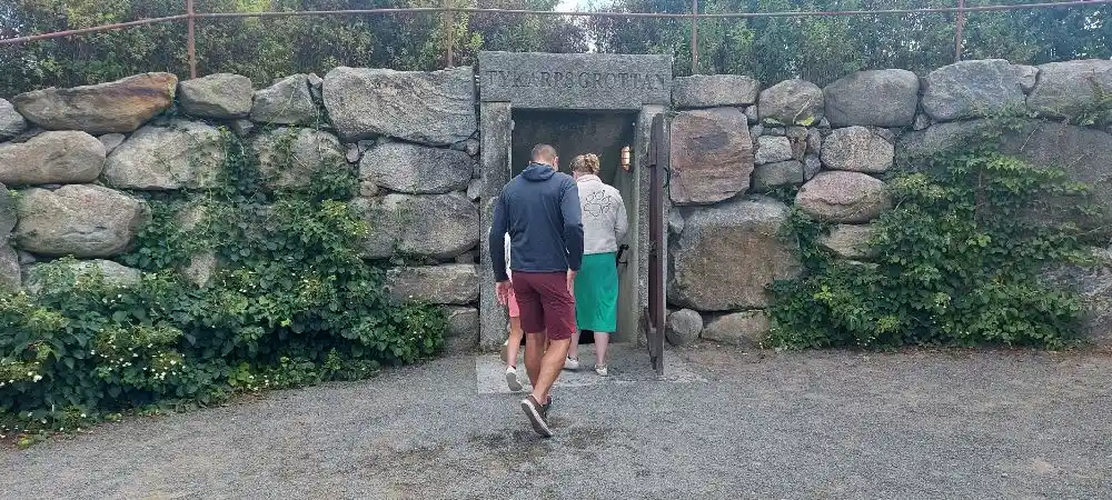 Alt-text: "Tykarpsgrottans camping med stenig terräng och stenmur, en naturnära plats för avkoppling och semester."