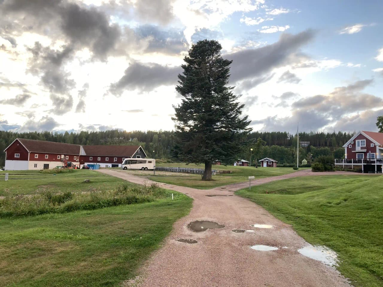 En naturskön golfbana med gröna grässlätter och ett lantligt hus i bakgrunden på Öjestrand GK.