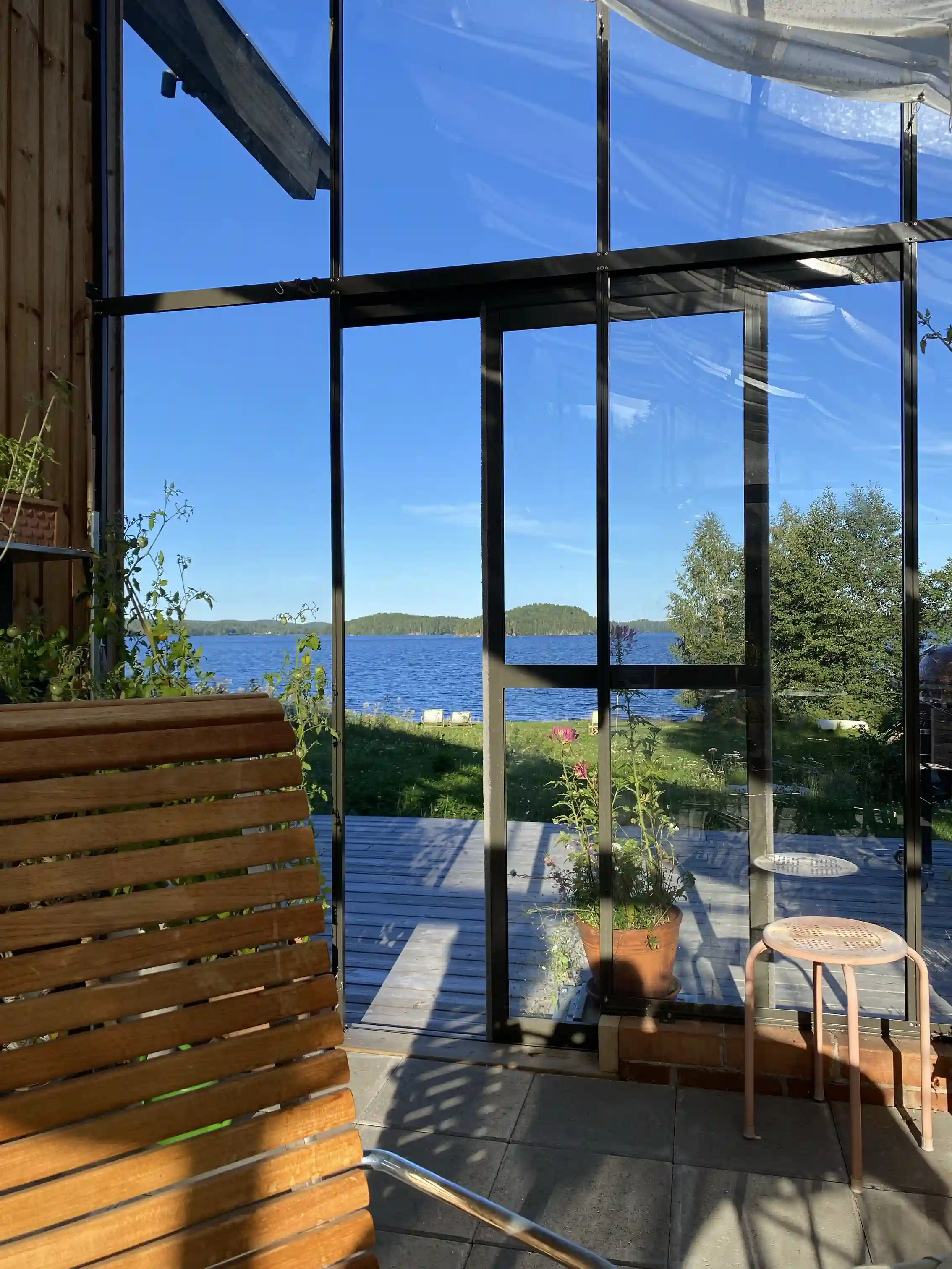 Alt-text: En veranda med skugga på Sagaliden, prydd med utemöbler, en blomkruka och växter, vilket ger en hemtrevlig och inbjudande atmosfär.