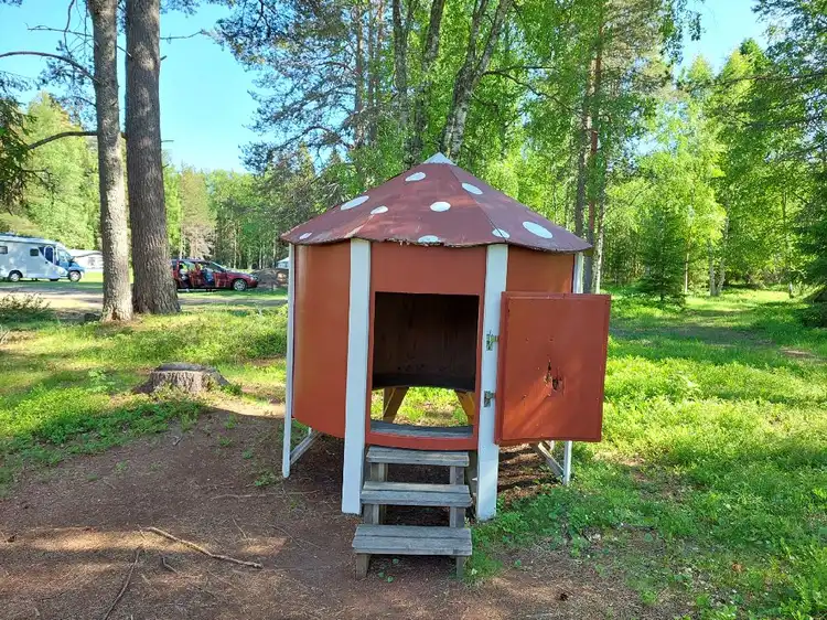 En campingplats med tält och en jurta omgiven av skog och grönska.