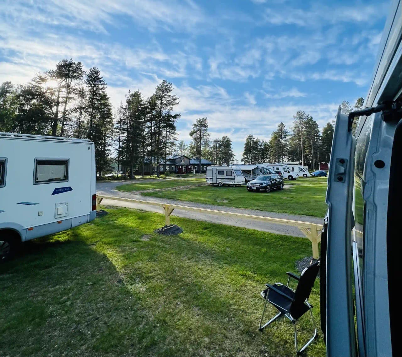 En bild av park med grön gräsmatta där flera husvagnar och mobila hem står uppställda. En semi-trailer lastbil syns i bakgrunden.