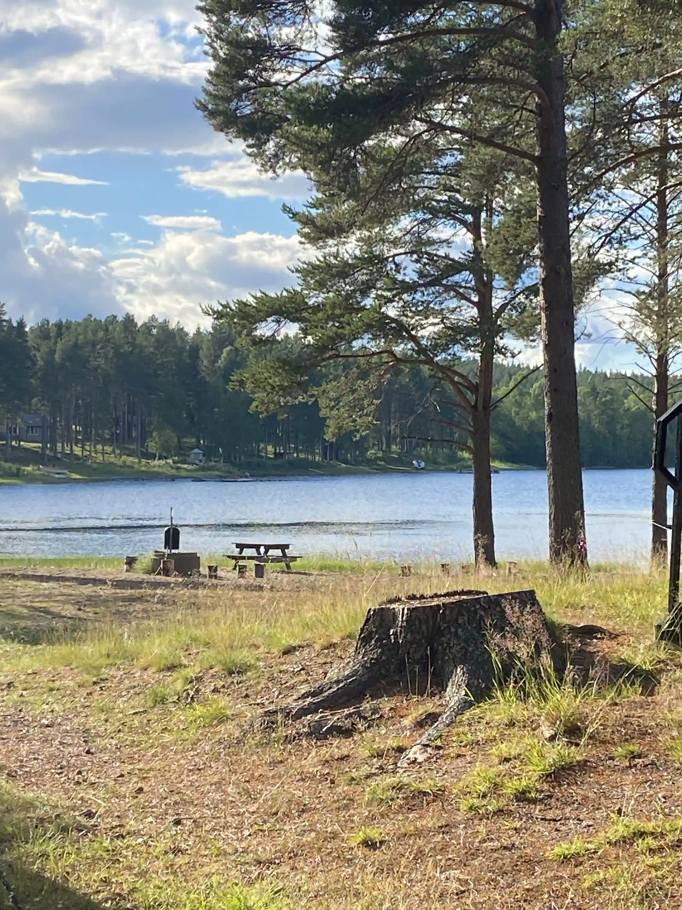 En fridfull sjö omgiven av grönskande landskap med en klar himmel i bakgrunden, vilket utgör en naturskön plats vid Vallens Turism & Fritid.