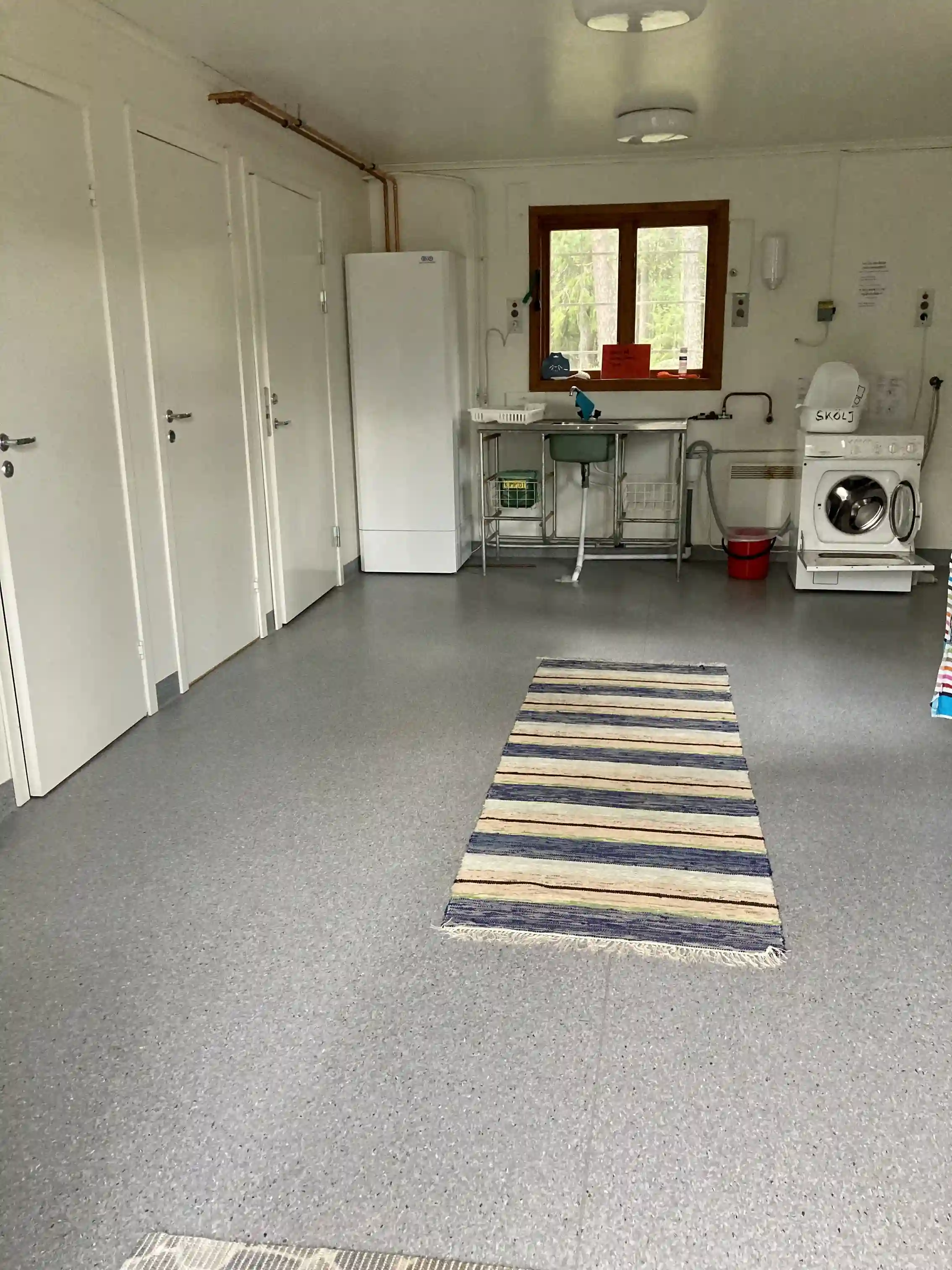 Ett rum med ljusa golvplattor, en dörr och en matta på golvet, skapar en inbjudande atmosfär på Vallens turism & fritid.