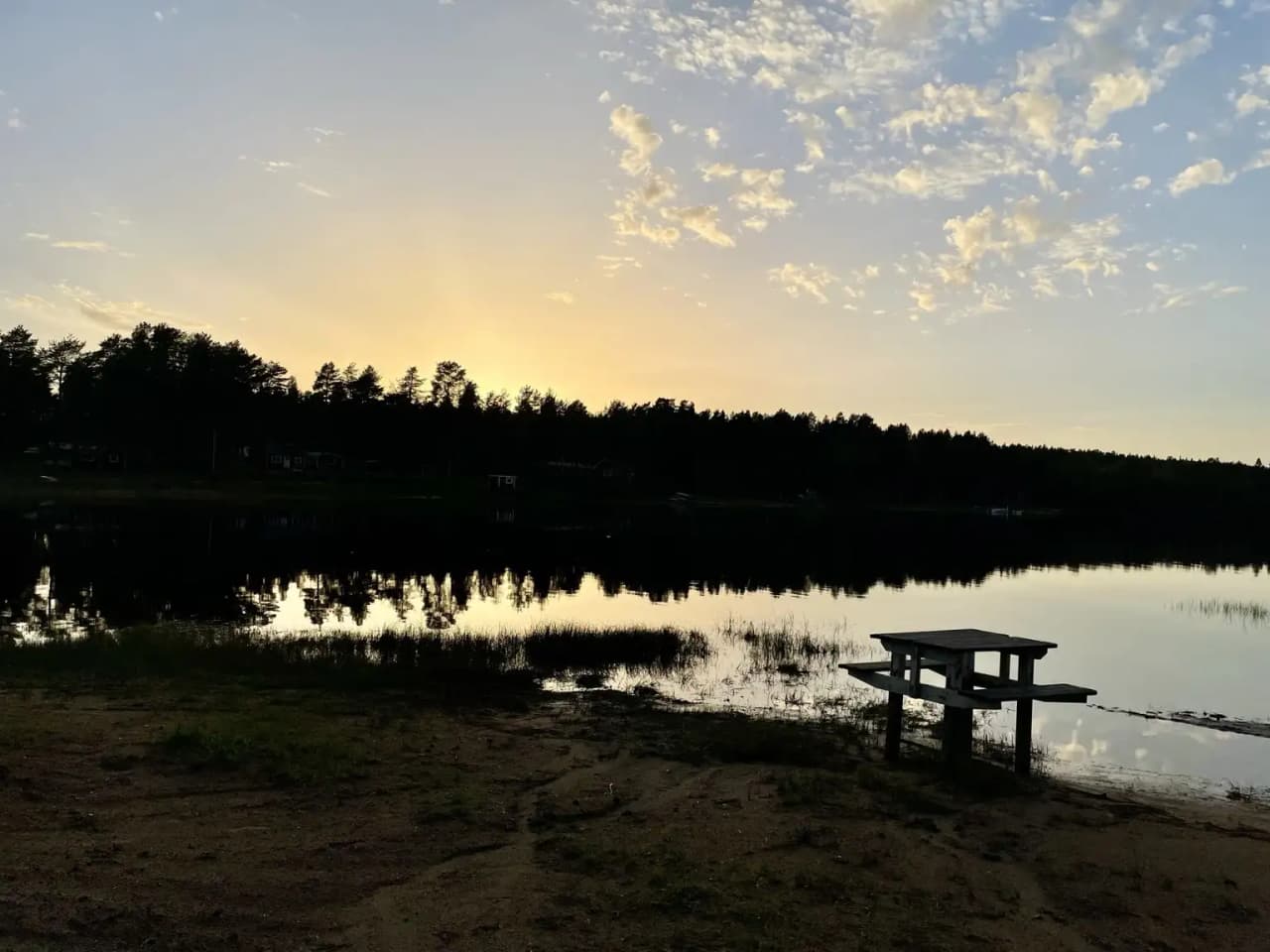 En vacker solnedgång över en spegelblank sjö, där himlen skiftar i mjuka färger och skapar en rofylld atmosfär vid Vallens turism & fritid.