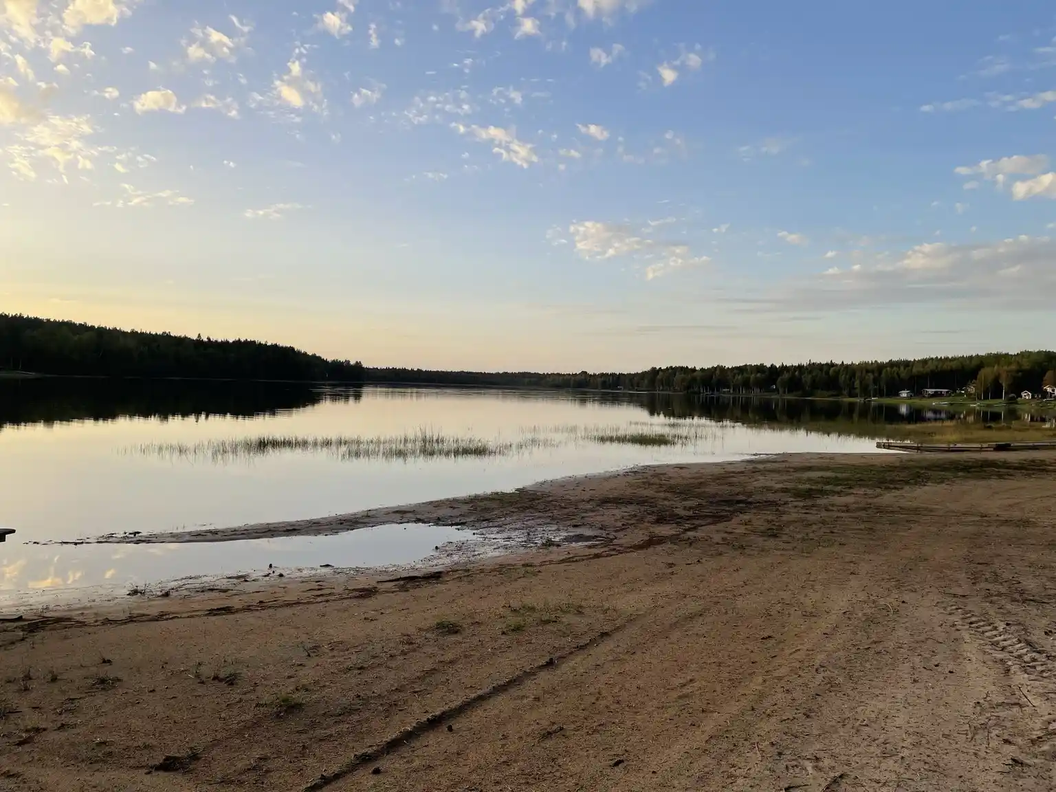 En naturskön vy vid Vallens turism & fritid, med himmel och horisont som speglar sig i ett stilla vattendrag och omgivande naturlandskap.